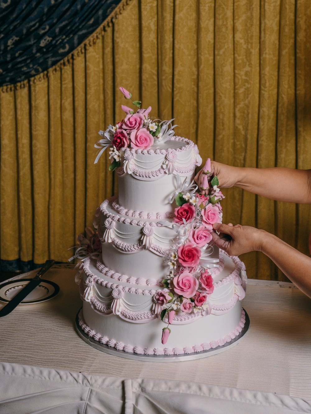 A three-tier bespoke celebration cake decorated with pink sugar roses