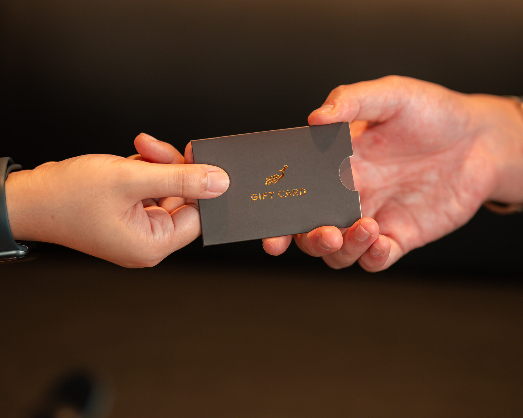 A Roasted Sip gift card being handed over between two people