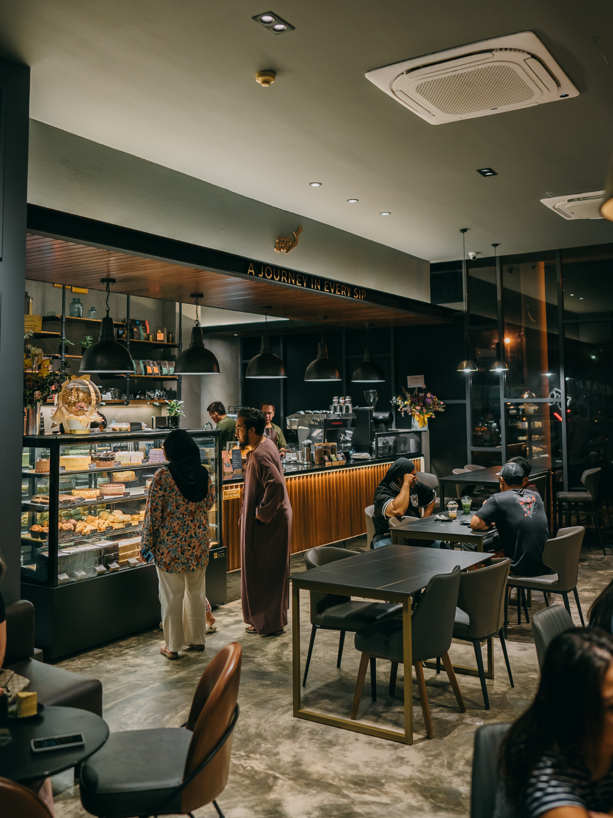 Roasted Sip Seria interior — A Journey in Every Sip with cake counter and brass pendant lights